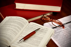 picture of legal books, pen, and glasses, which could all be used by a wrongful death attorney