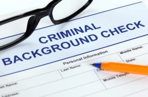 Glasses and pen on top of a criminal background check application
