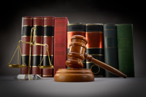 Scales of justice, law books and gavel over dark background