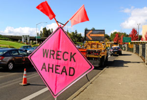 pink road sign stating "wreck ahead" implying there may be an 18 wheeler accident ahead