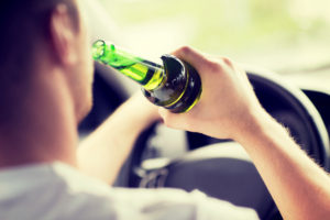 a man drinking beer and driving