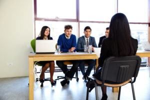 woman sitting at a job interview with four people interviewing her