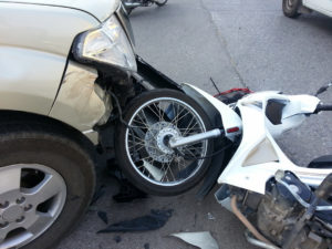 White motorcycle under a car after a motorcycle vs car accident.