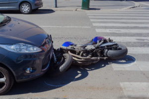 Motorcycle under a car in an intersection after a motorcycle accident. 