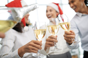 three employees of a company enjoying glasses of champagne at their office holiday party