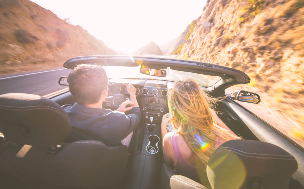 Couple driving fast on a sport convertible car in the canyons. Romantic road trip